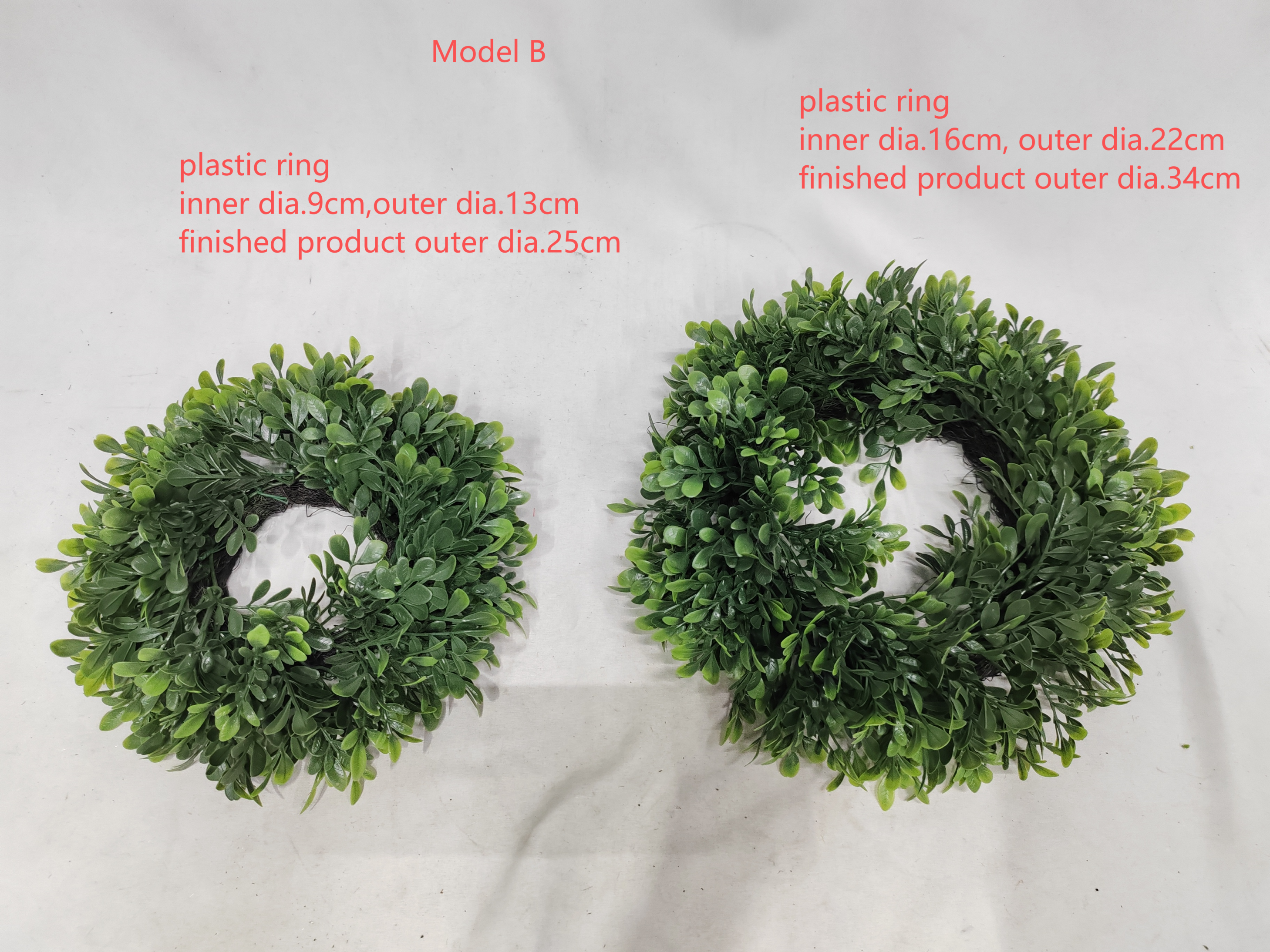 Two artificial green leaf wreaths on a white surface, labeled Model B, with text showing inner and outer diameters for plastic ring sizes.